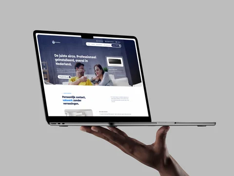 AircoMaxx-website op een laptop in een hand, met de homepage en uitleg over persoonlijk contact.
