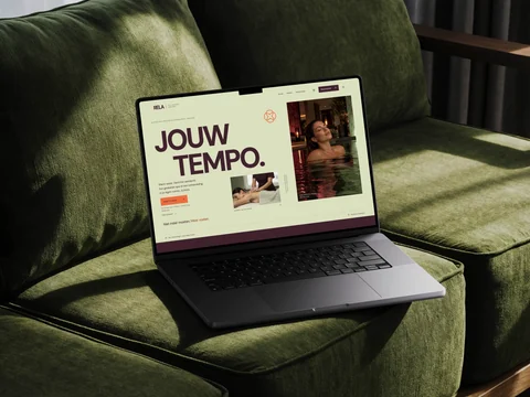 RELA-homepage op een laptop op een groene bank, met pistache, bordeaux en de boodschap Jouw tempo.