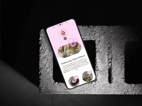 Taloor Bakery-homepage op een telefoon op beton, met desserts en de roze merkidentiteit.