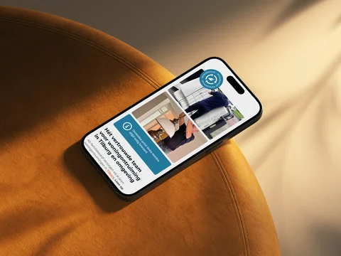 Telefoon op een oranje poef met het team en de werkwijze van Woningopfrisser.