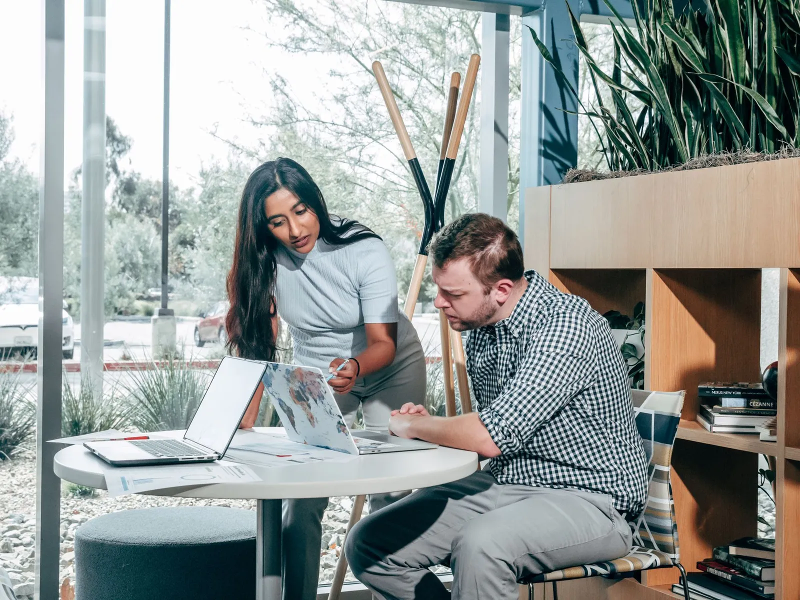 Twee mensen bespreken hun werk aan een bureau met laptops.