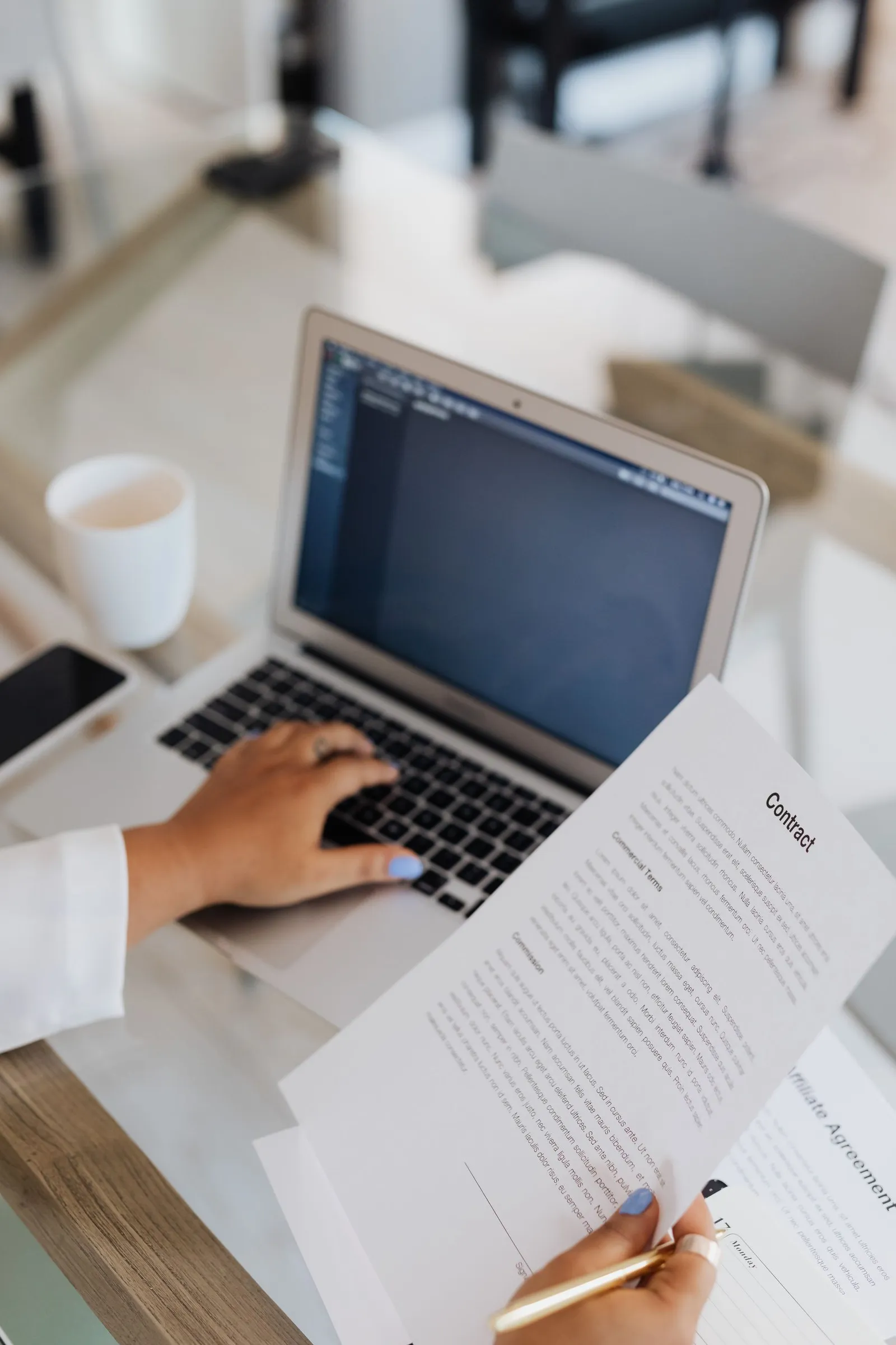 Een document wordt naast een laptop gelezen en beoordeeld.