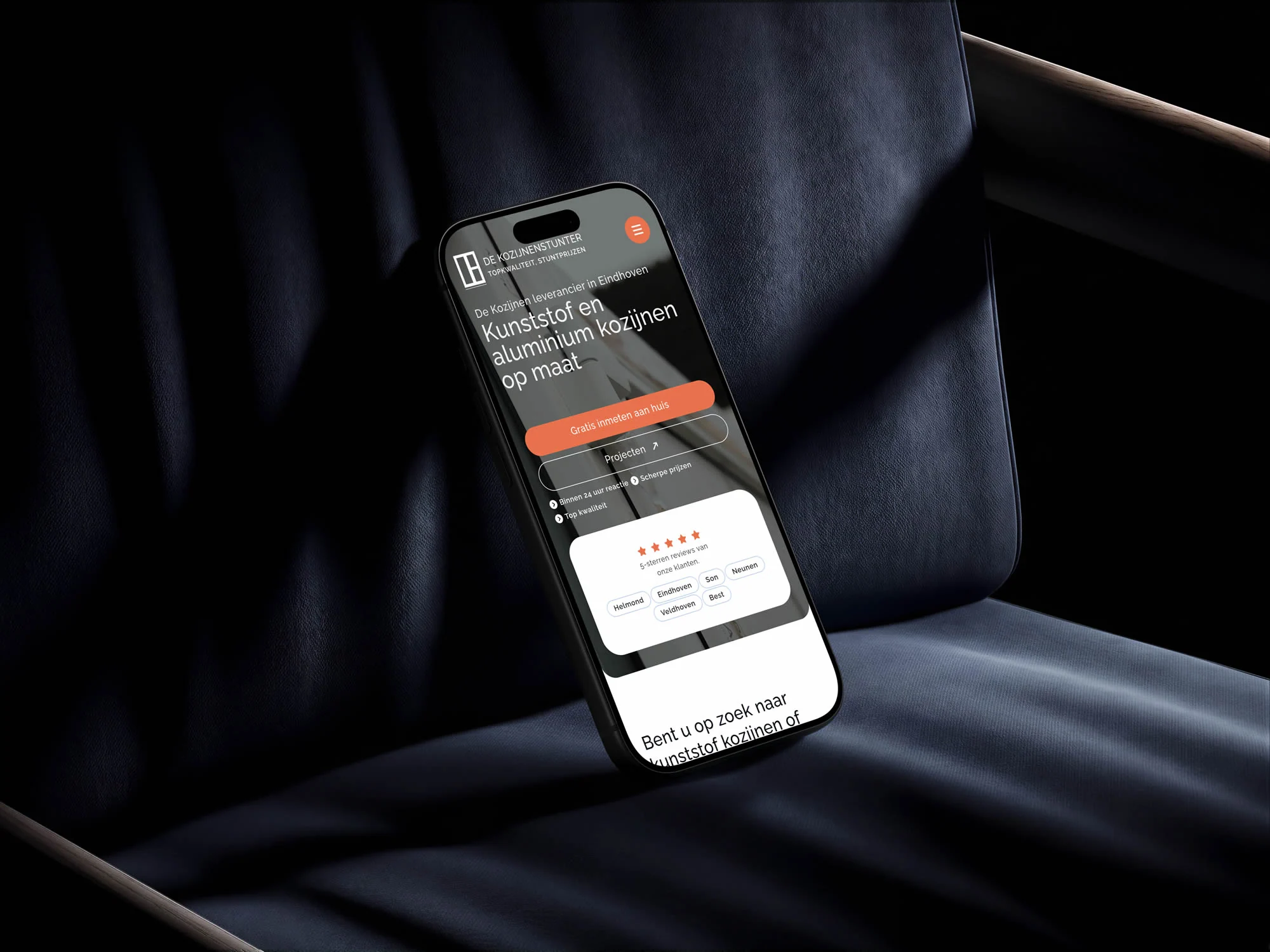 De Kozijnenstunter-homepage op een telefoon op een donkerblauwe stoel.