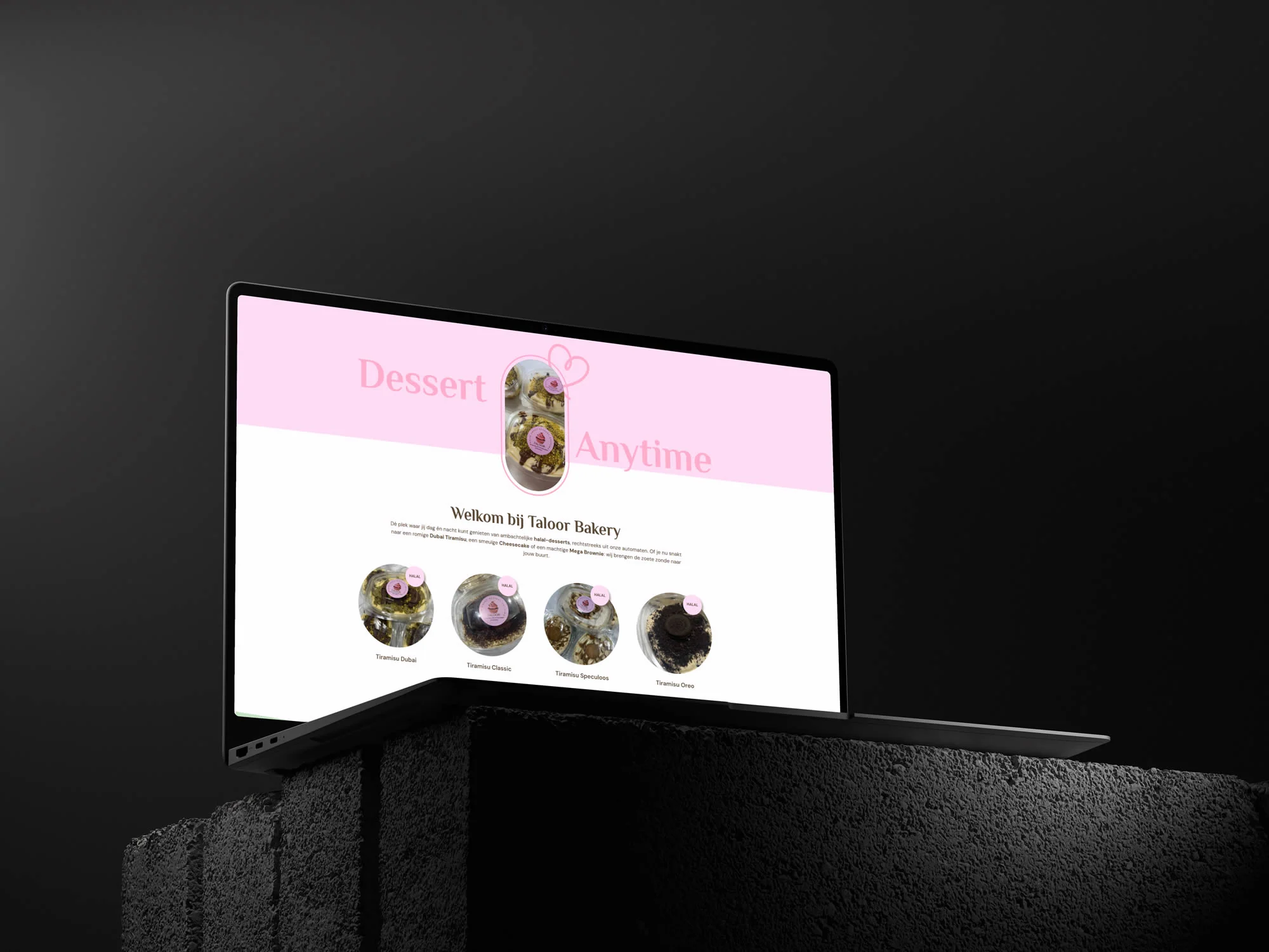 Taloor Bakery-homepage op een laptop boven donkere betonblokken, met de roze Dessert Anytime-presentatie.